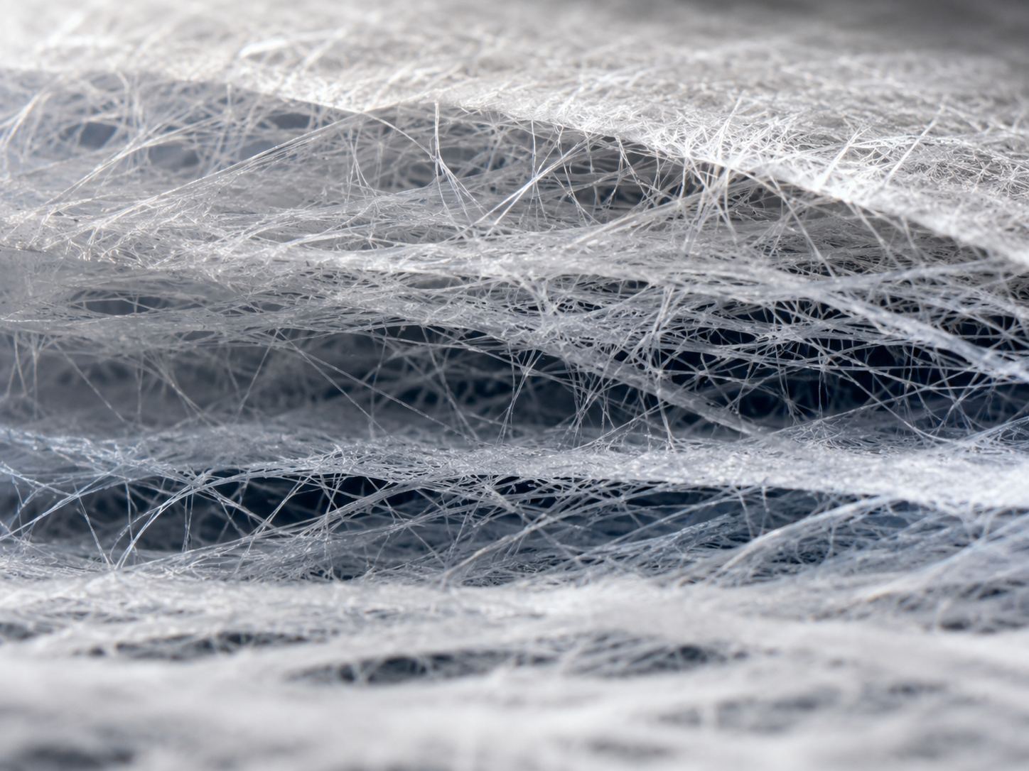 Macro view of layered HEPA filter media fibers under light, showing fiber spacing and density